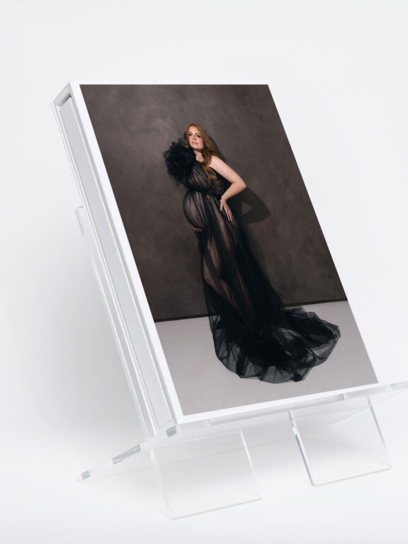 Luxury portrait album displayed on an acrylic stand featuring a fine art maternity photograph